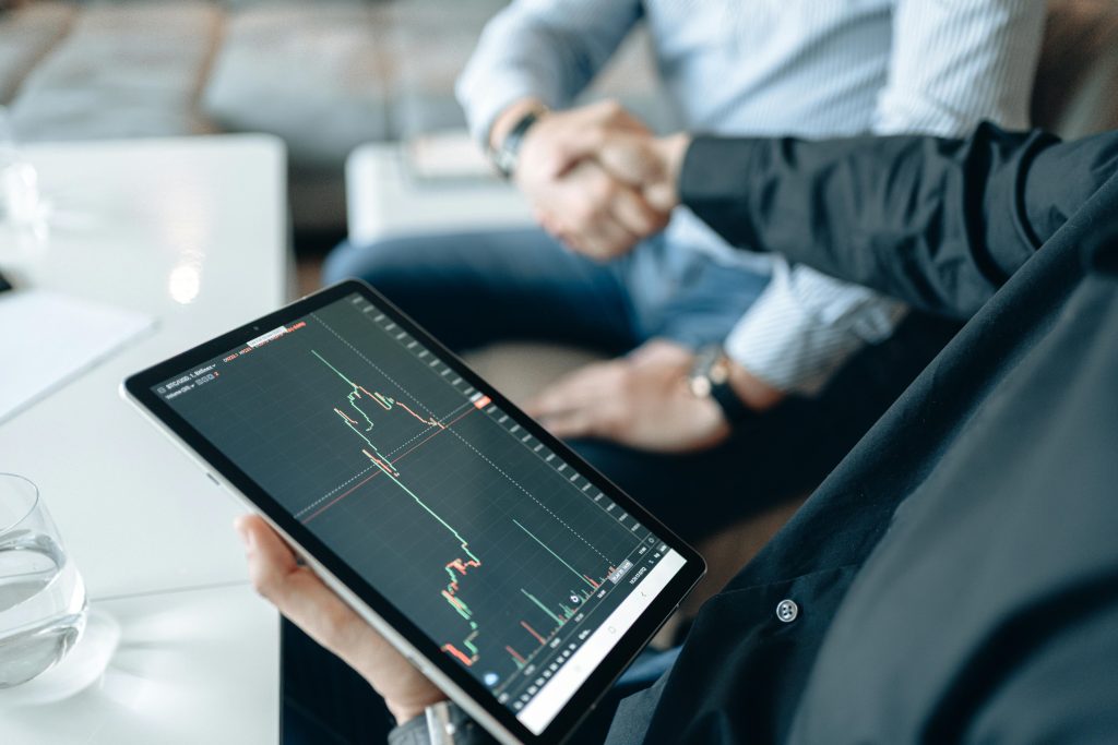 Small‑business executives shaking hands while reviewing data on a tablet.